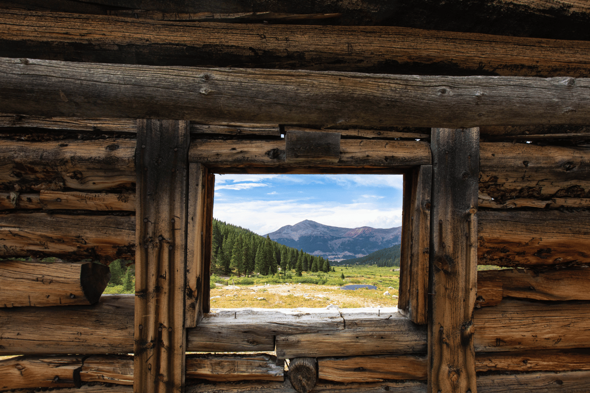 Mountain landscape through a window from an old cabin